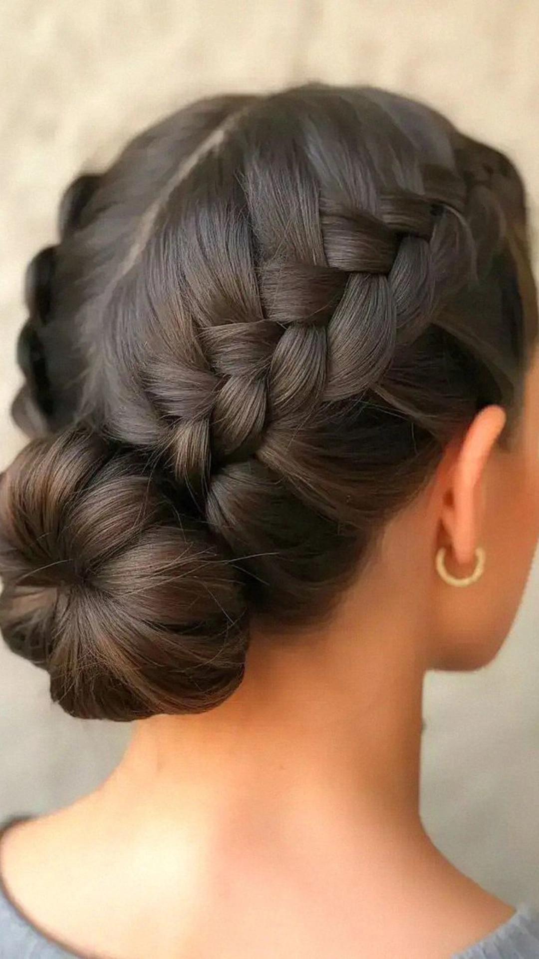 Braided updo styled into a low side bun with a hoop earring