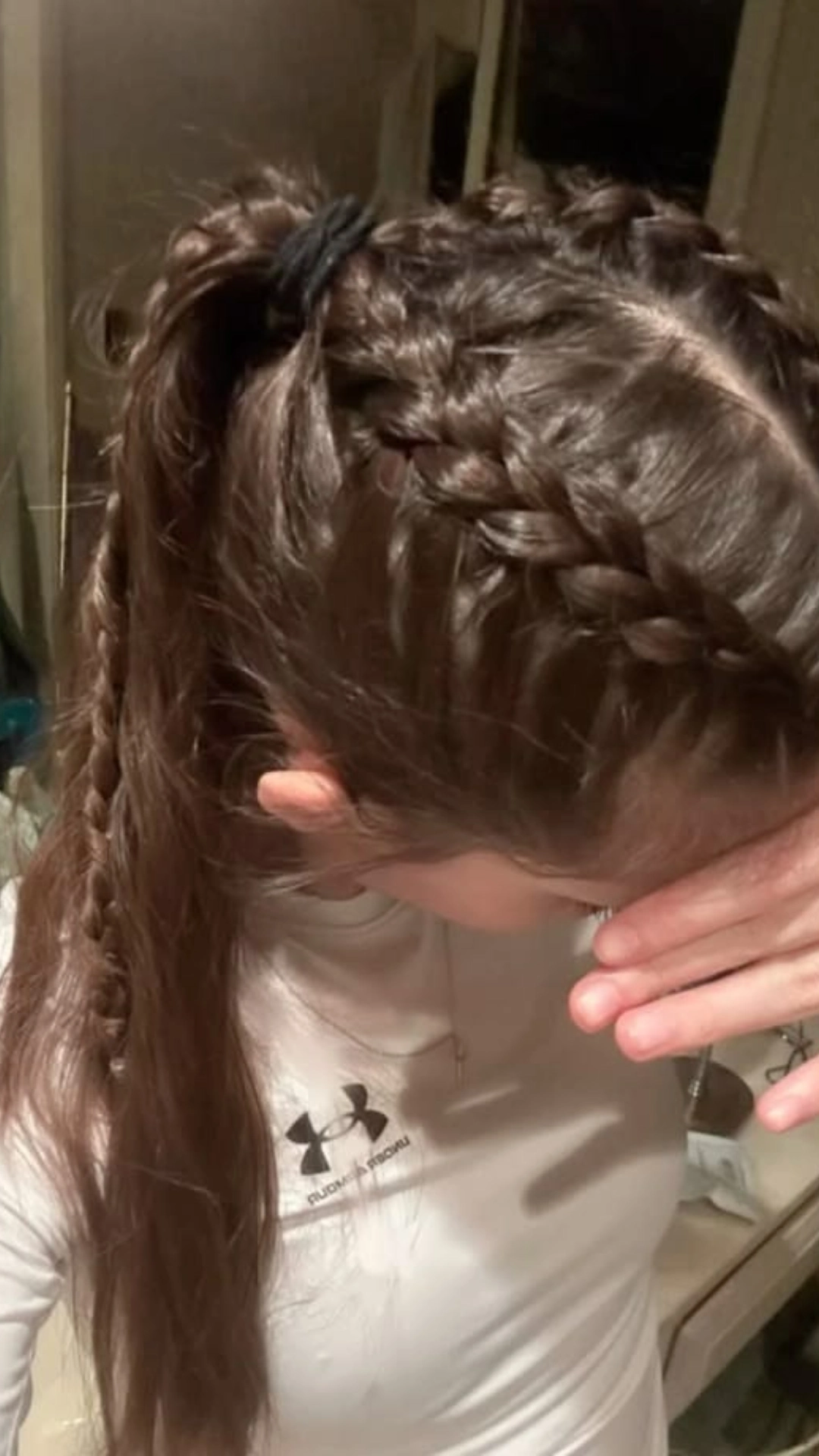 Braided pigtails being styled, secured with a hair tie