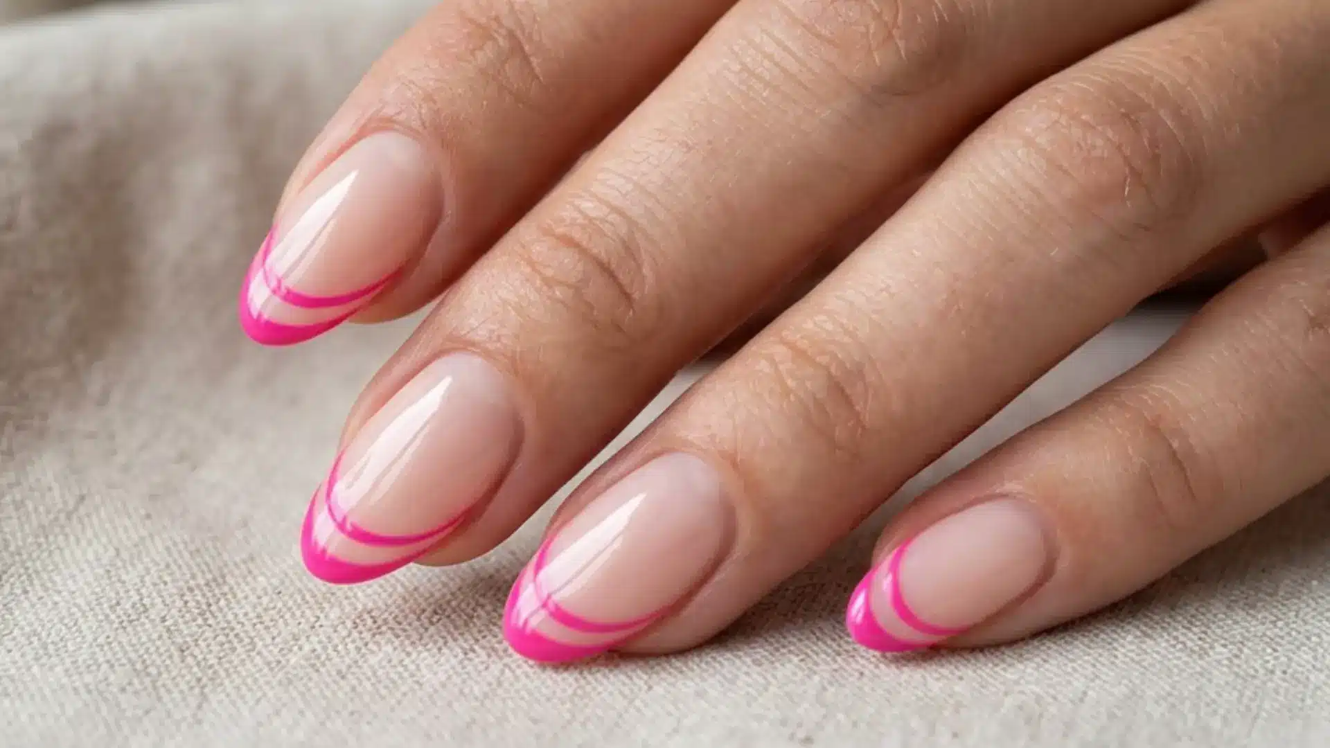 double lined hot pink French tip on nude almond nails with two thin parallel pink lines at the tip