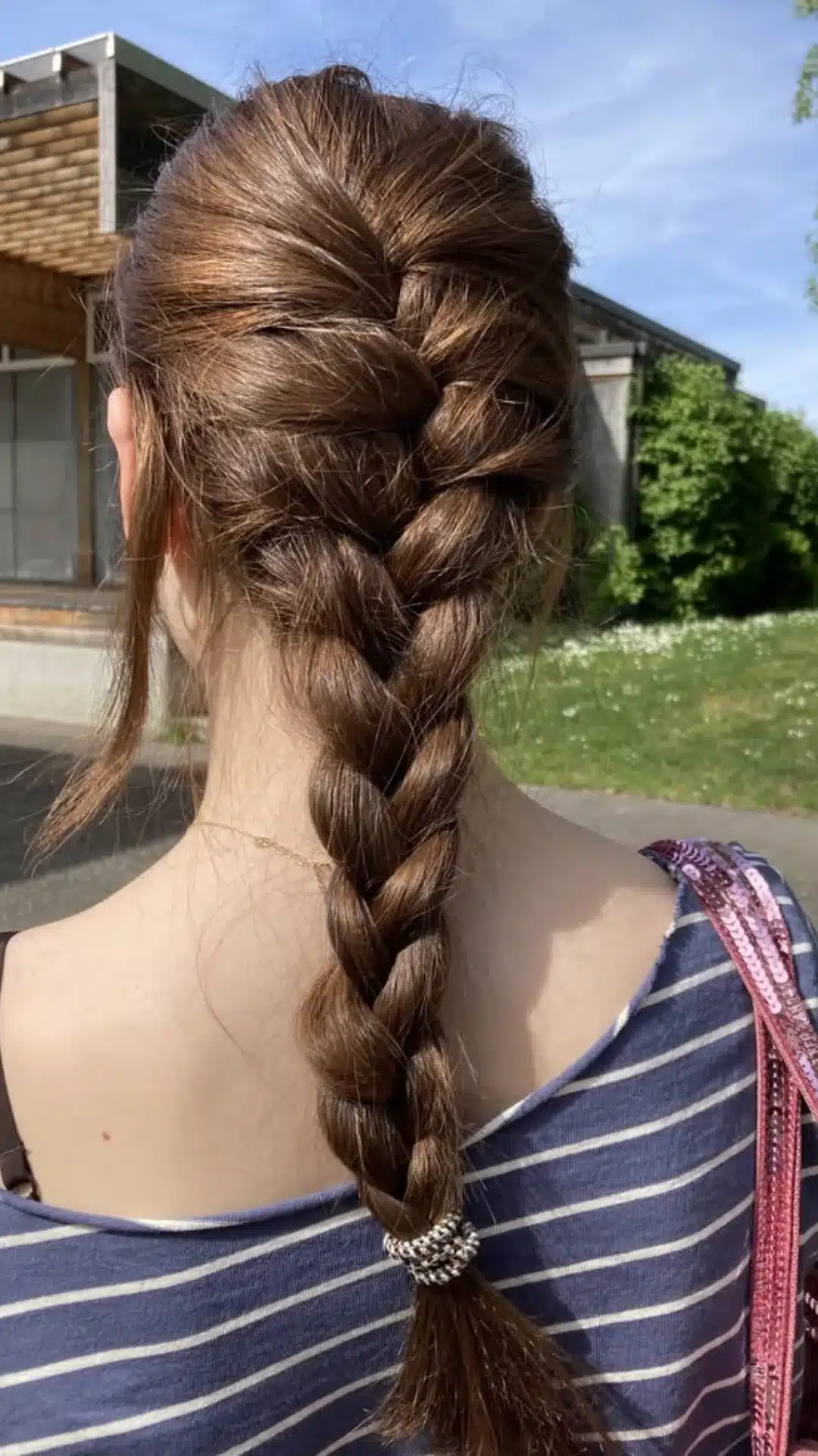 Loose French braid styled down the back with face framing pieces