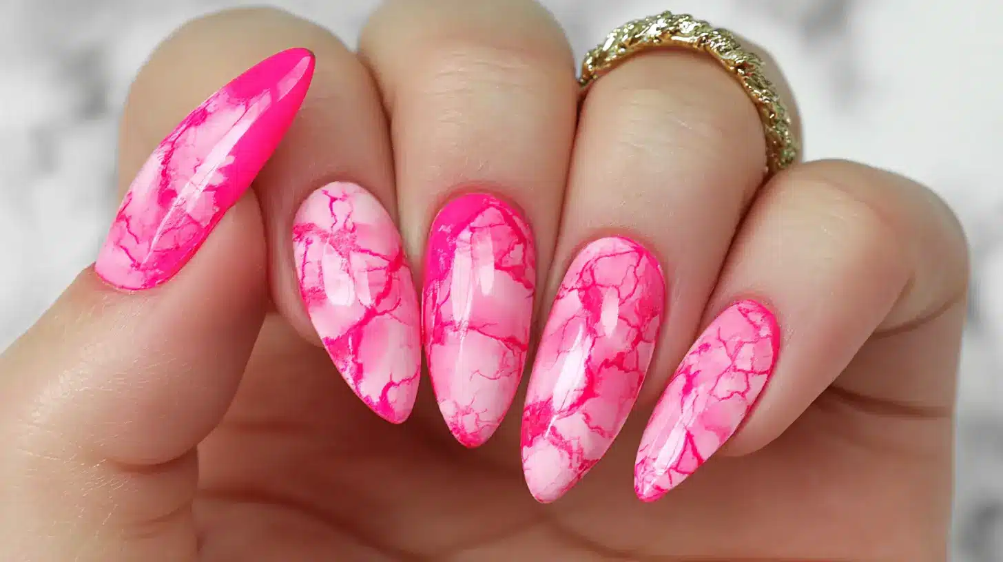 hot pink marble nails with bright pink veining on a pale pink base with a gold statement ring