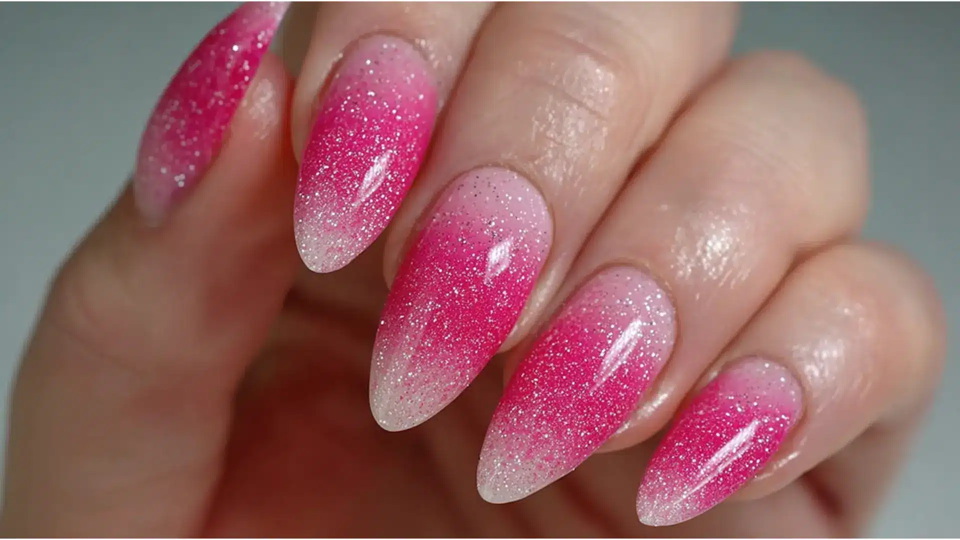hot pink ombre glitter almond nails fading from bright pink at the base to clear glitter at the tips