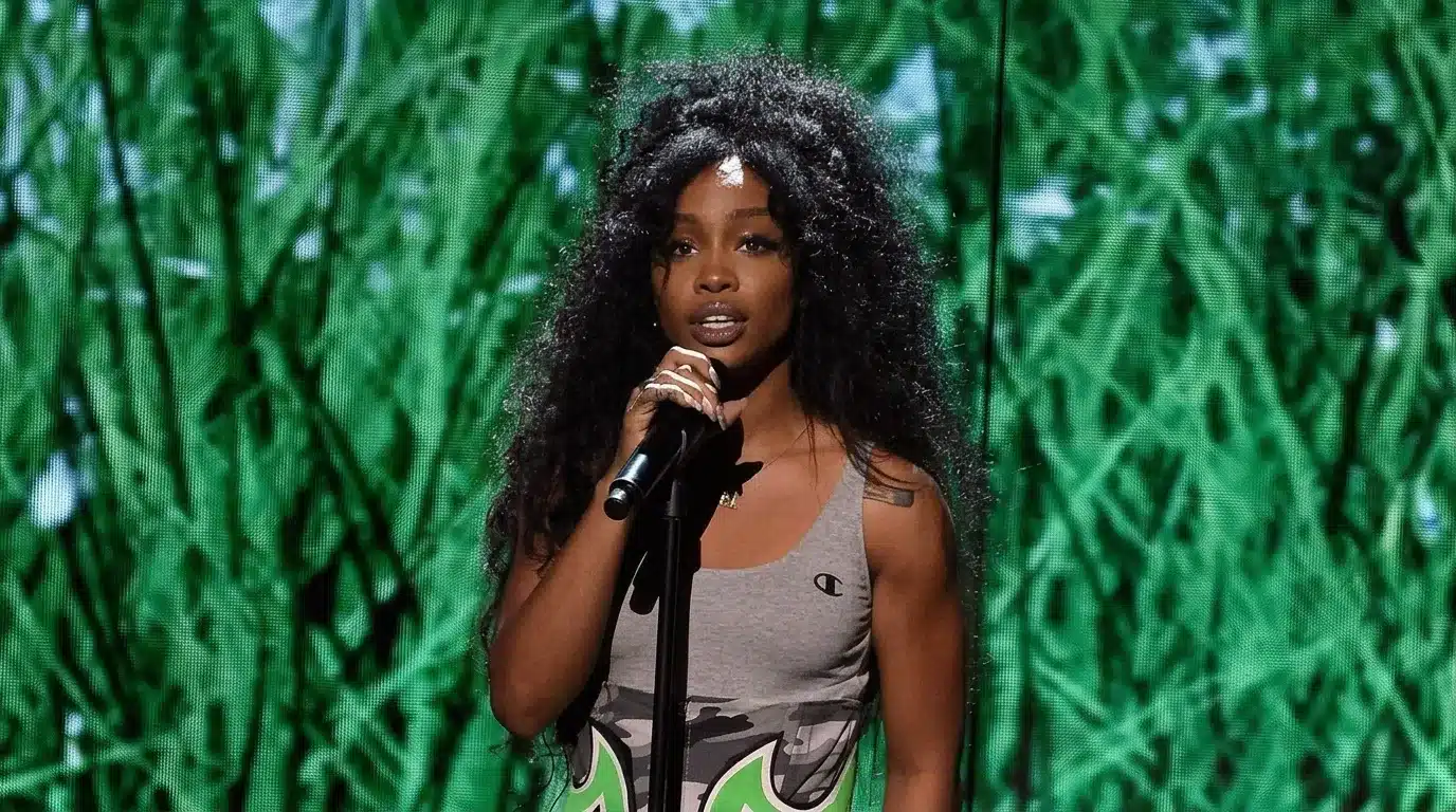A woman with long hair engaged in singing, holding a microphone in a performance setting.