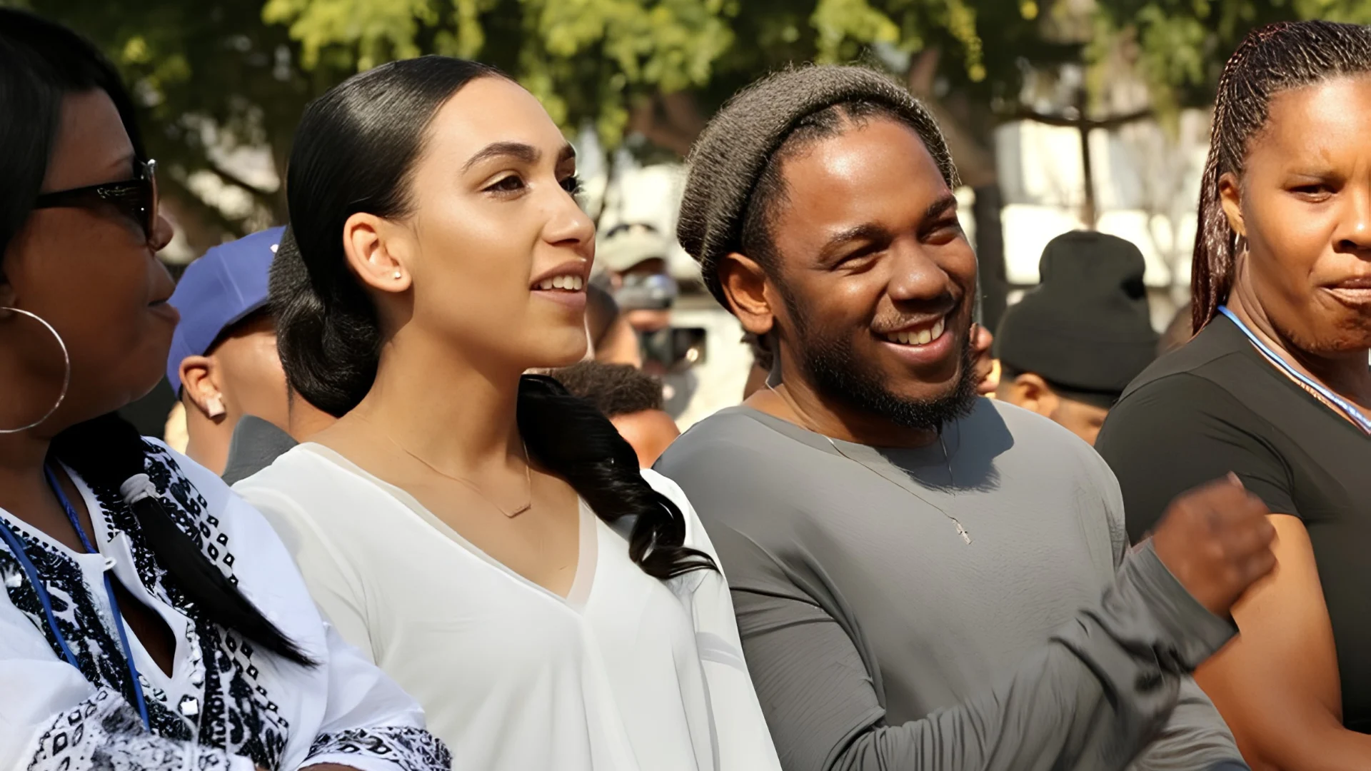 Kendrick Lamar smiles with Whitney Alford while standing in a crowd with other people