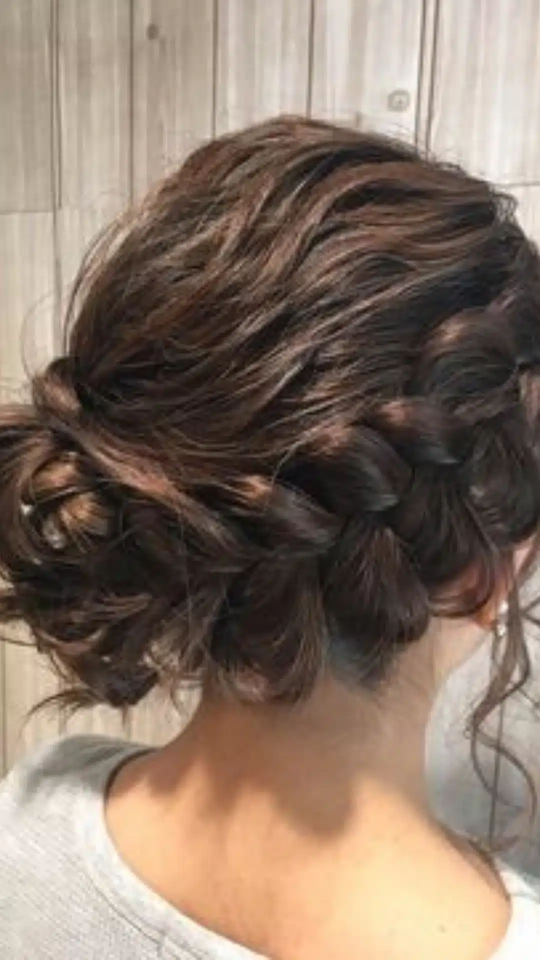 Messy side braid twisted into a low bun with loose face framing pieces