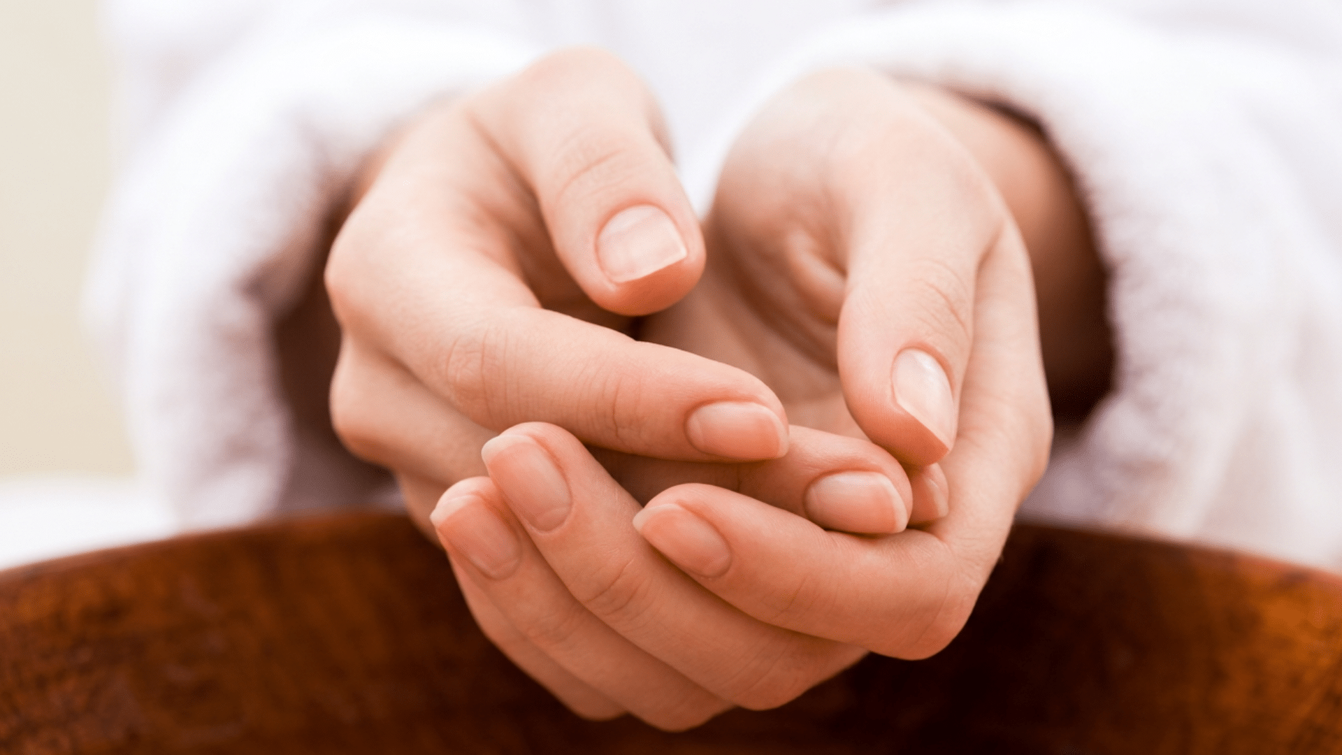 Close-up of clean, natural fingernails with healthy cuticles as a person gently examines their nails with both hands.