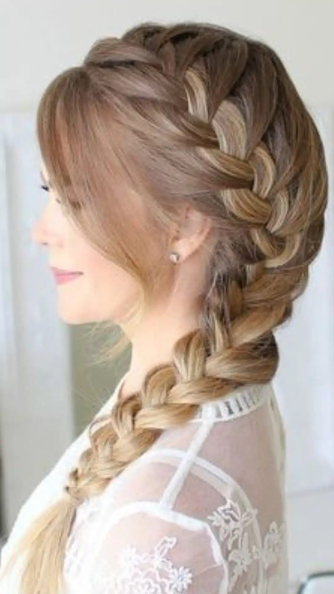 side view of a thick side french braid on long blonde hair with soft face framing layers simple braided hairstyle for long hair