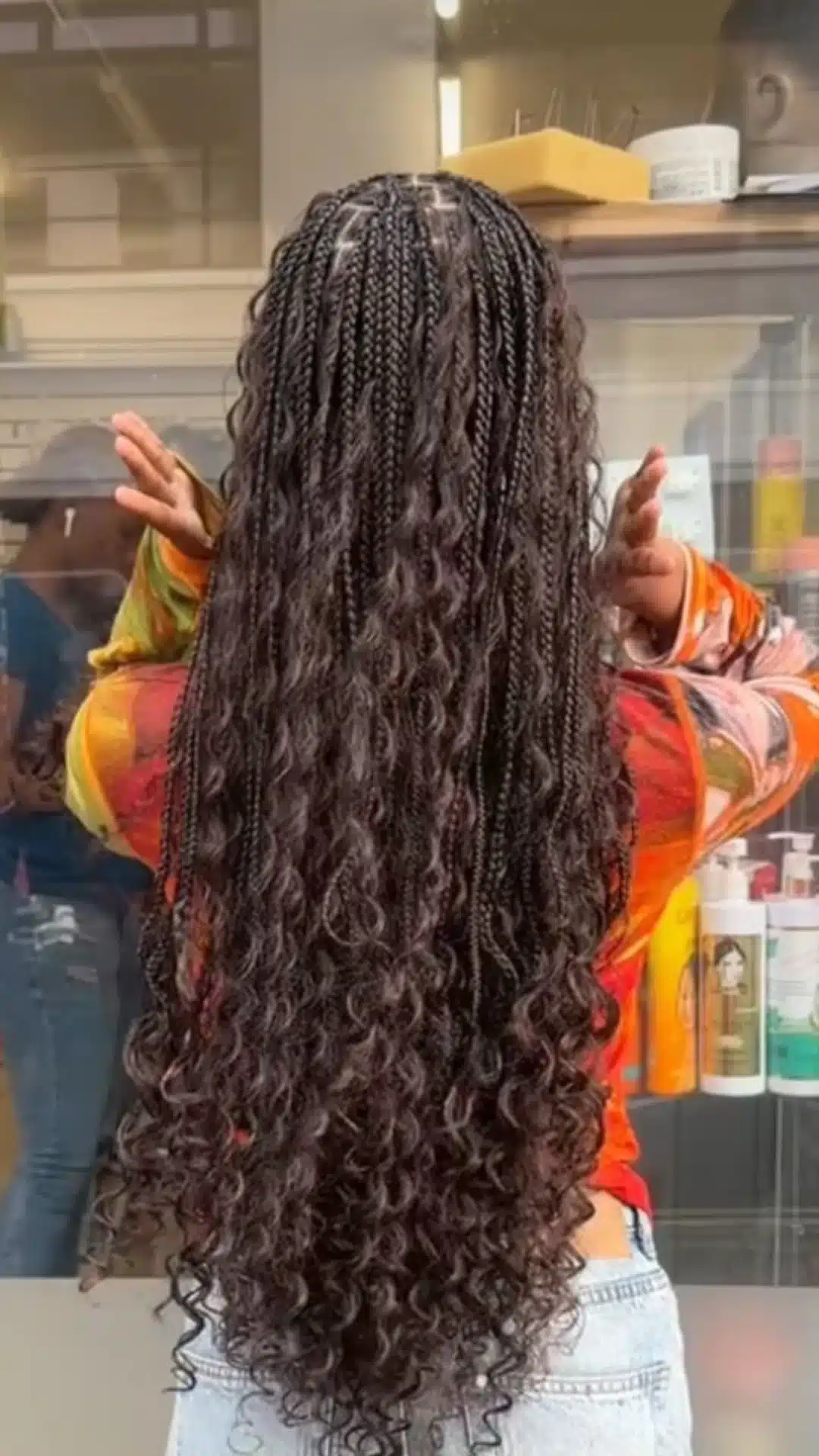 black girl with waist length boho braids featuring loose curly strands full length protective hairstyle back view