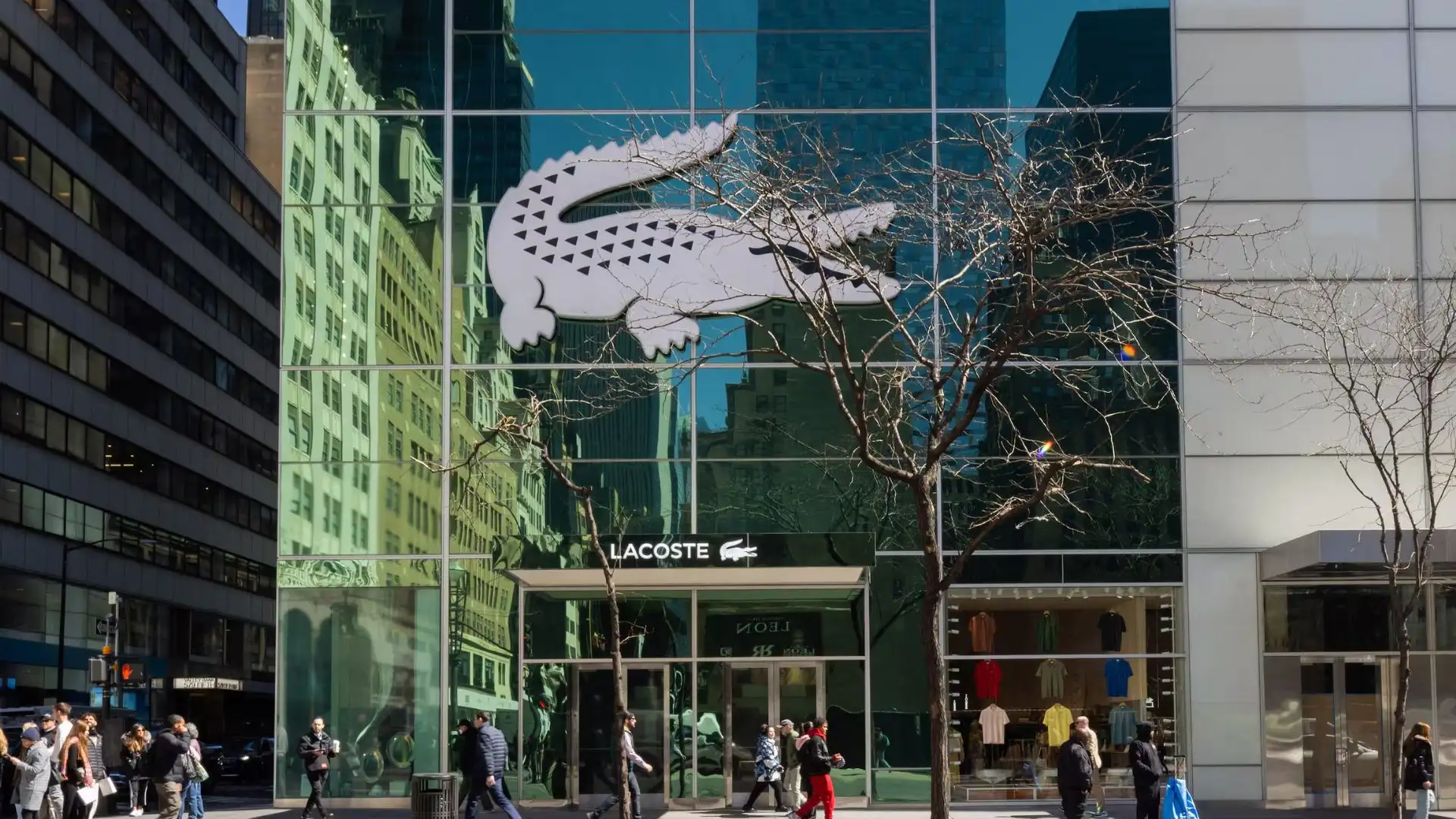 A large alligator rests against the side of a building, showcasing its scaly skin and powerful physique.
