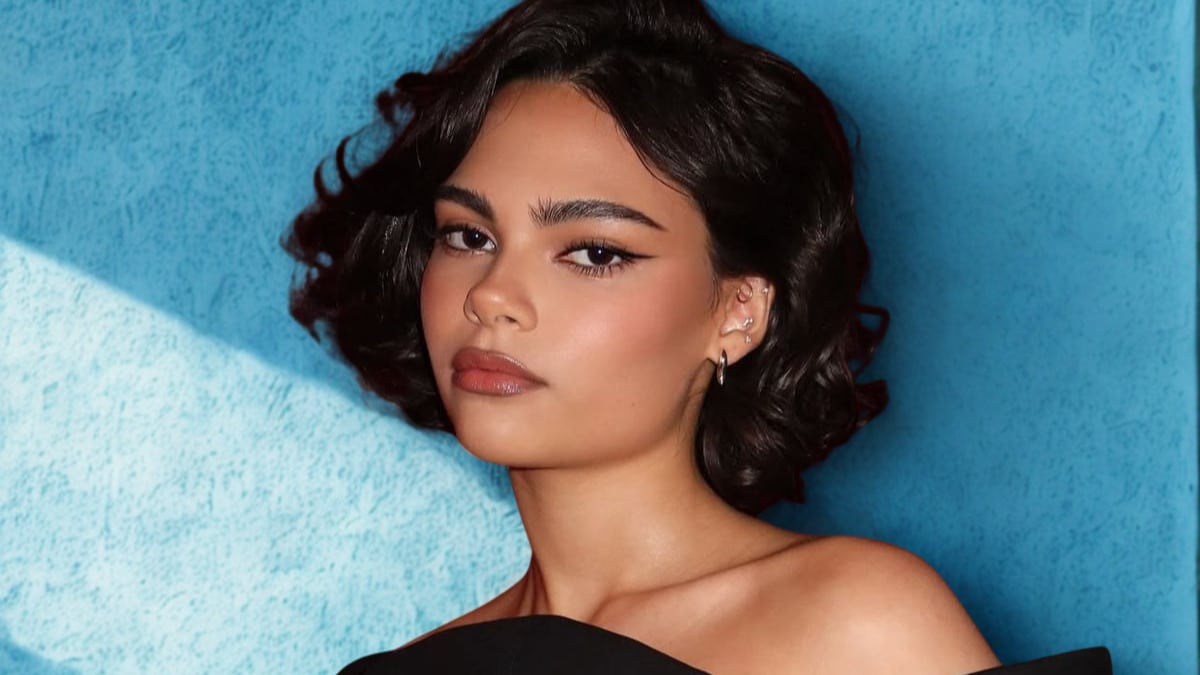 Ariana Greenblatt with short hair wearing a black dress, posing confidently against a neutral background.