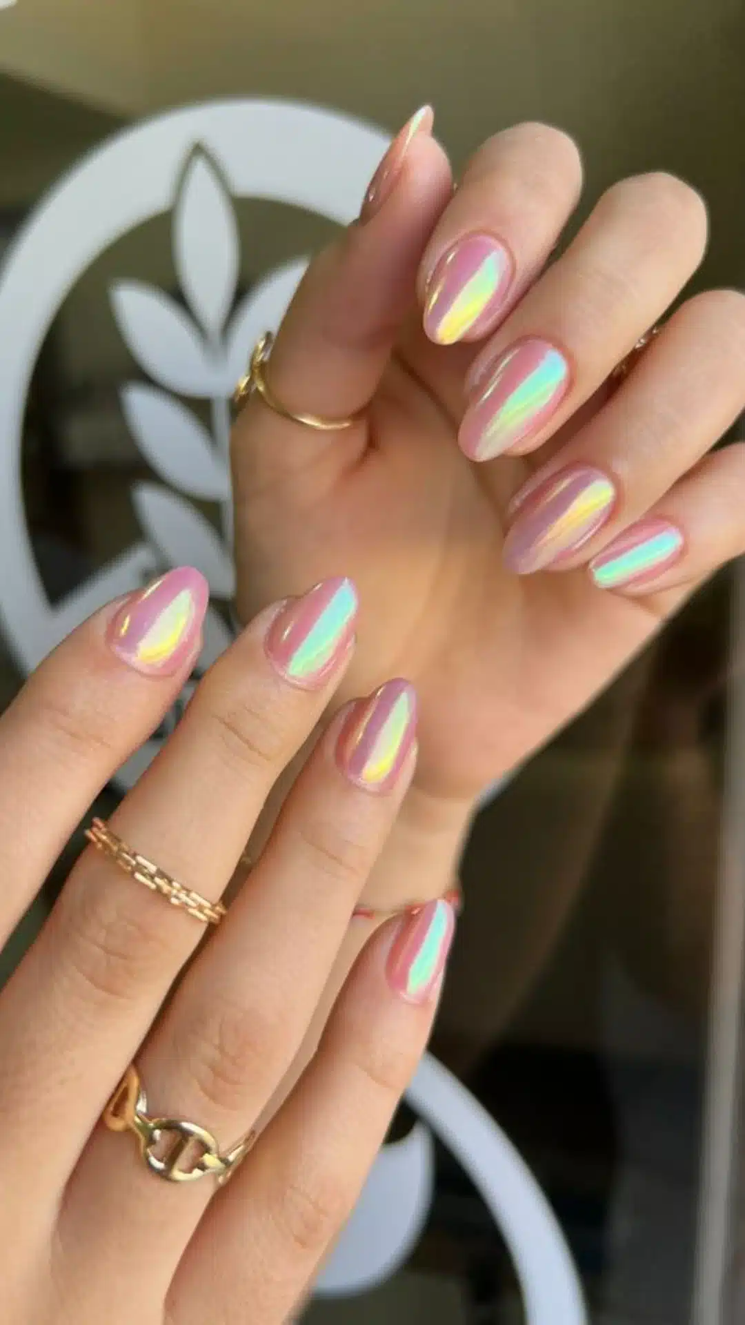 Close-up of a woman's hand with pink and gold nails, showcasing a beautiful ring held delicately
