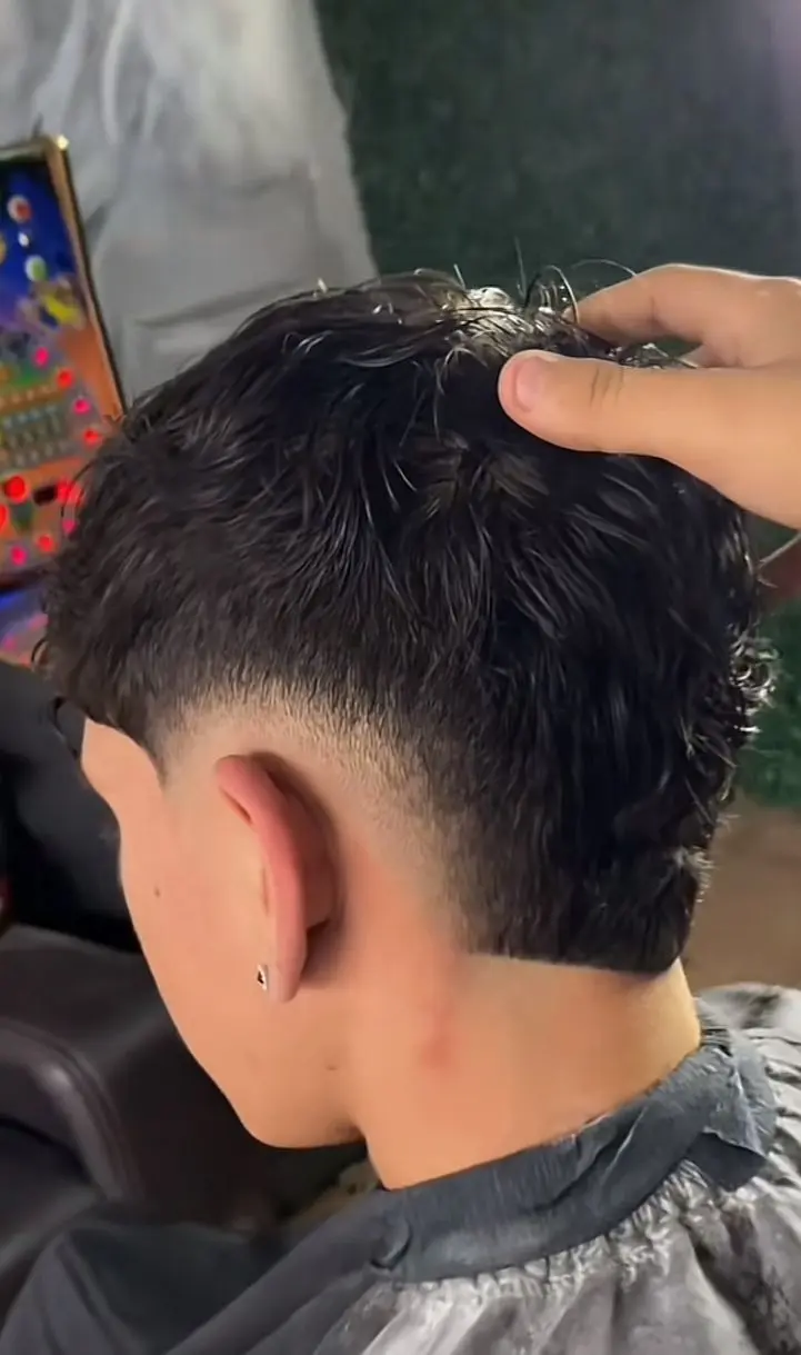 Burst fade haircut with a tapered fade around the ears and a longer textured back