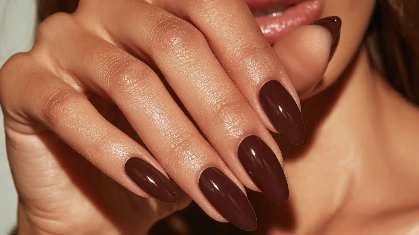 Close-up of almond-shaped nails painted in rich chocolate brown gel polish with a smooth glossy finish and elegant salon-quality shine.