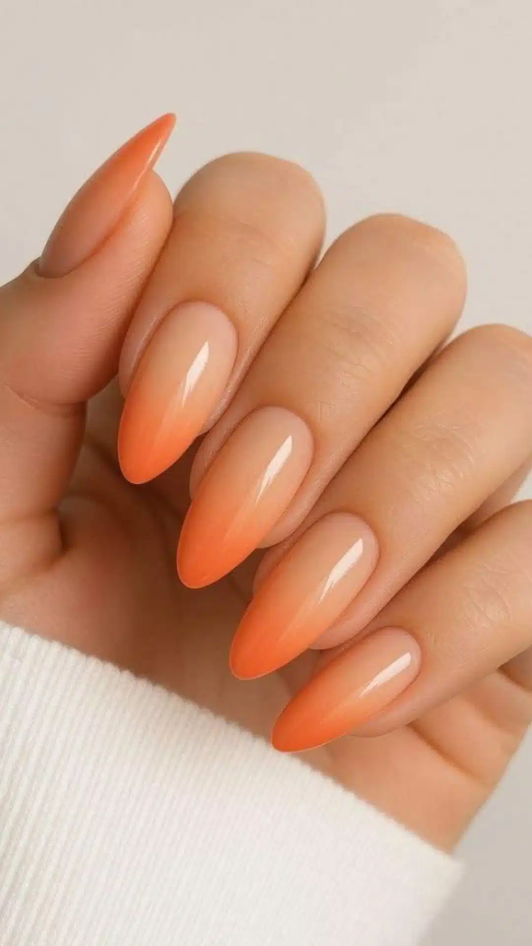Almond-shaped nails with a coral to nude ombre fade