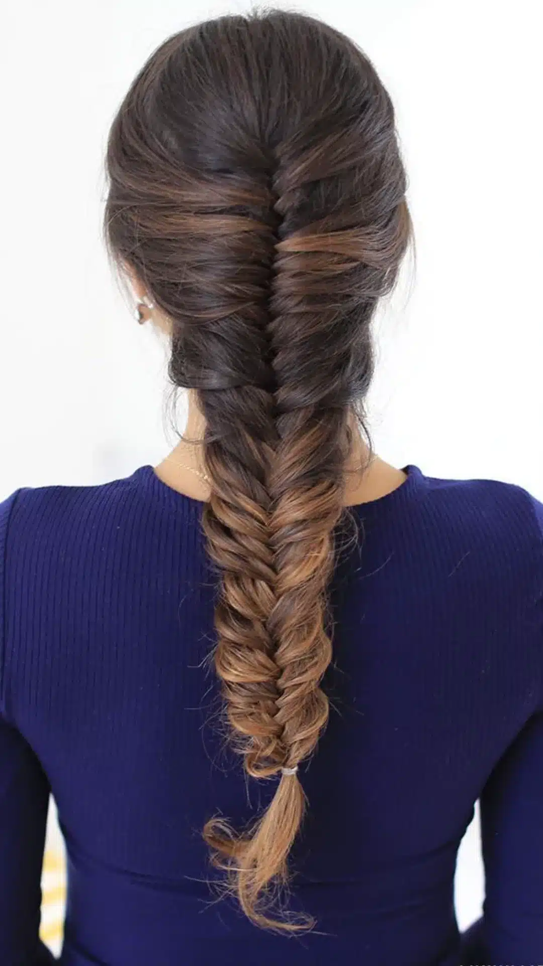 back view of a loose french braid on brunette hair with soft woven sections creating an elegant everyday braided hairstyle
