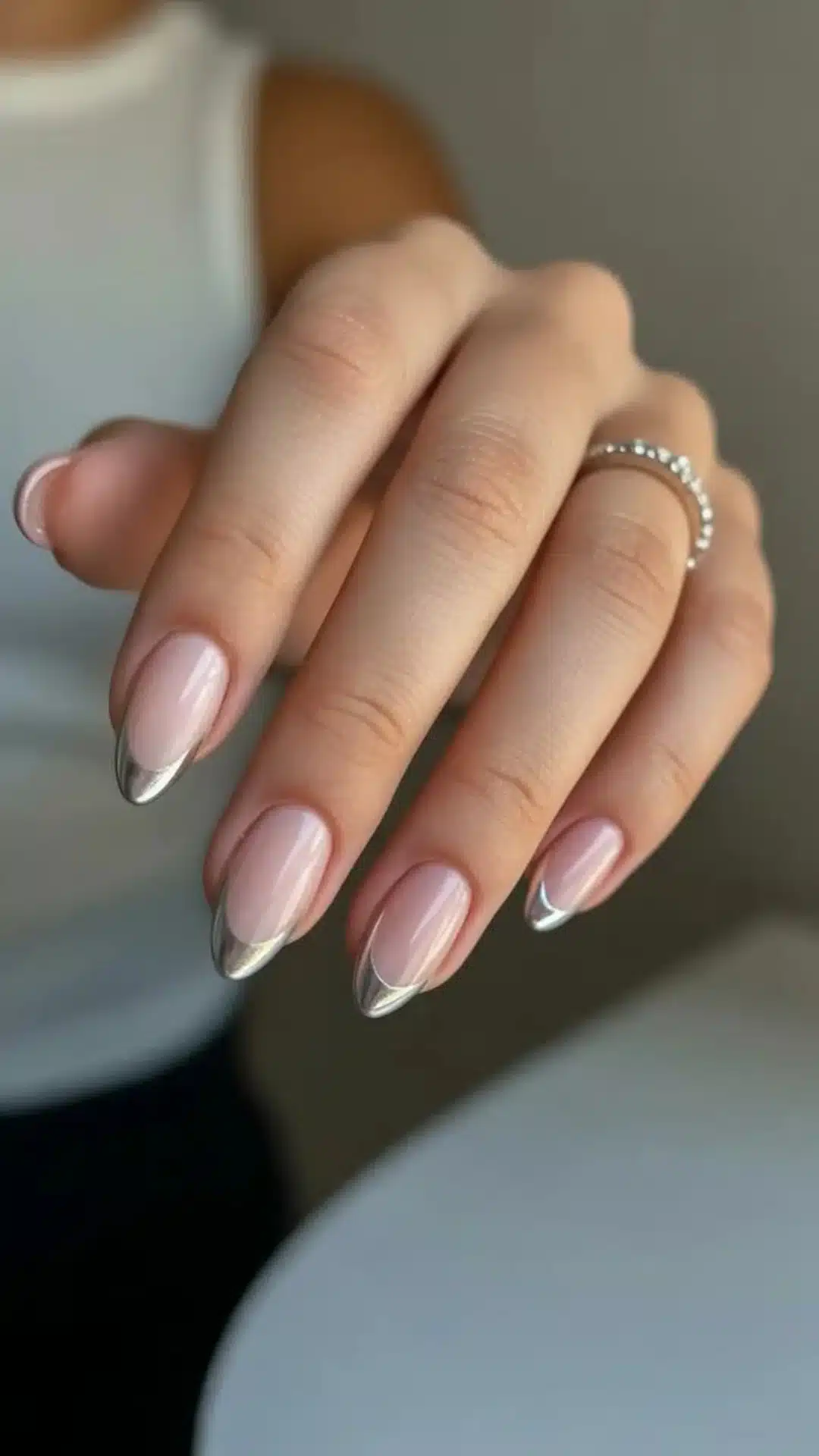 A close-up of a woman's hand displaying a french chrome tip nails.