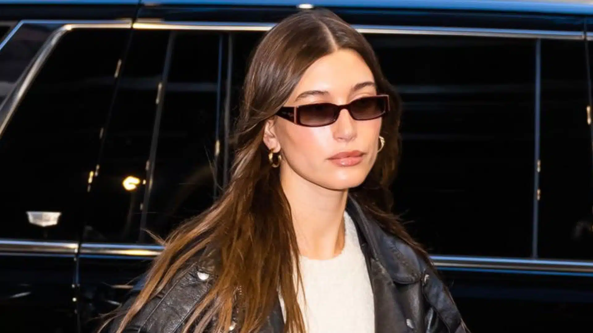 Hailey Bieber wearing stylish glasses, showcasing a chic look that complements her outfit and hairstyle.