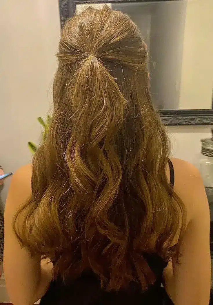 Long wavy light brown hair styled in a half up half down hairstyle adding volume while keeping greasy roots less noticeable