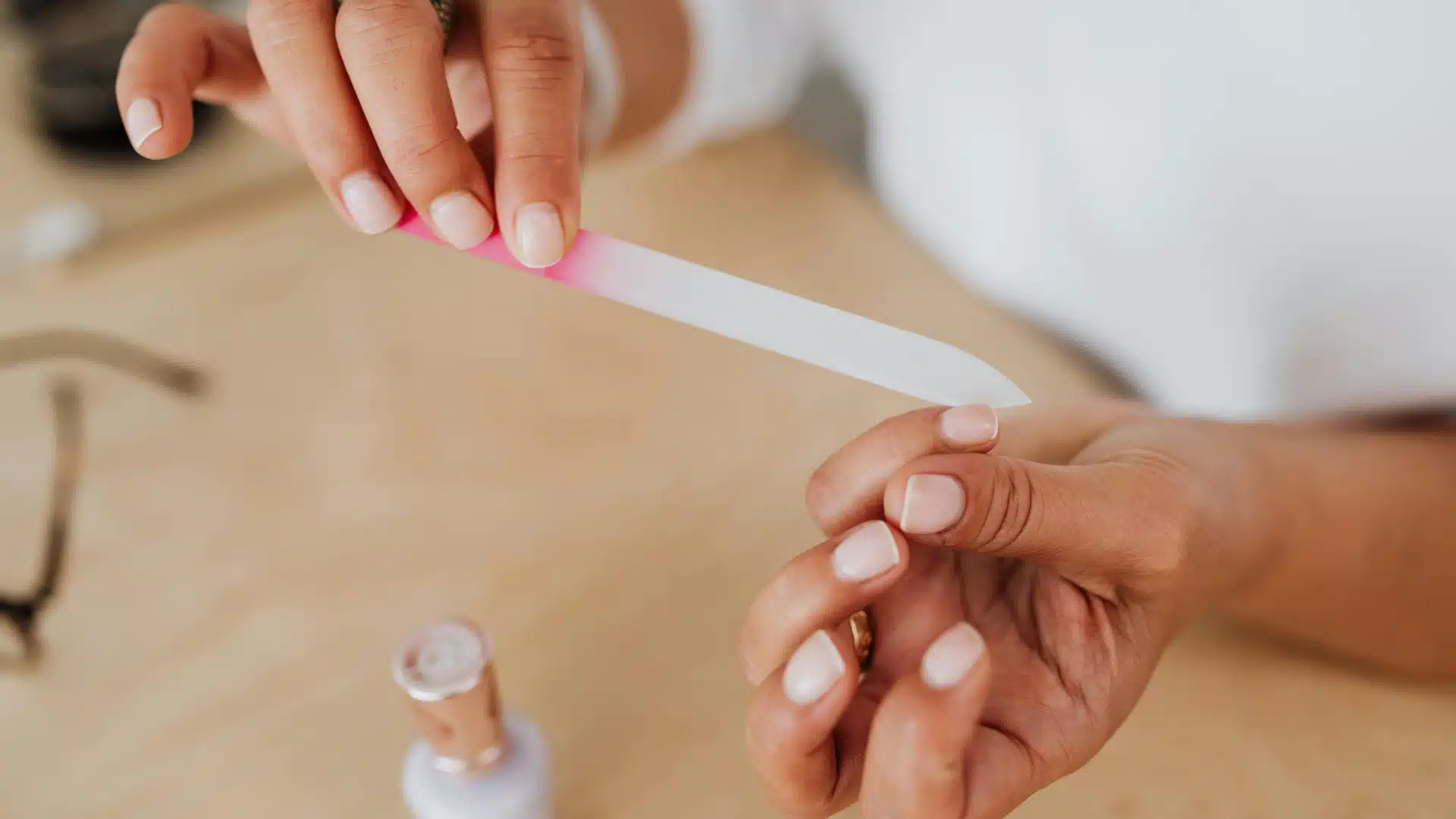 A woman grips a pink nail file, showcasing her focus on nail maintenance and beauty