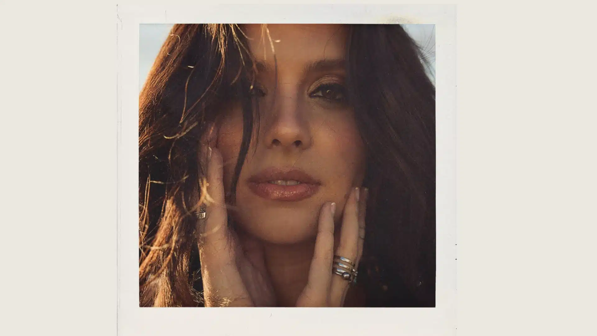 Lanie Gardner in a close-up portrait with dark hair and hands on her face.