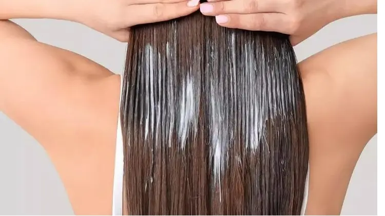 Leave in conditioner is being applied to hair, the hair is straight and fine, it is medium brown-black.