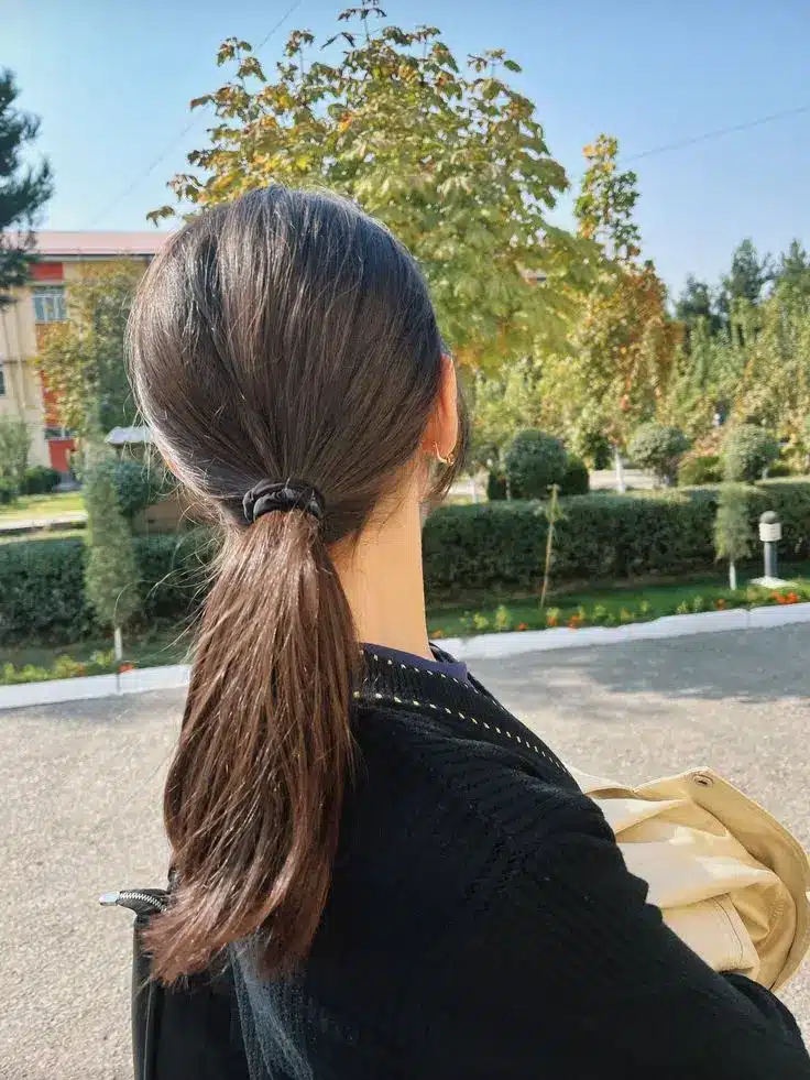 Back view of dark brown hair styled in a sleek low ponytail with smooth roots creating a simple hairstyle that hides greasy hair