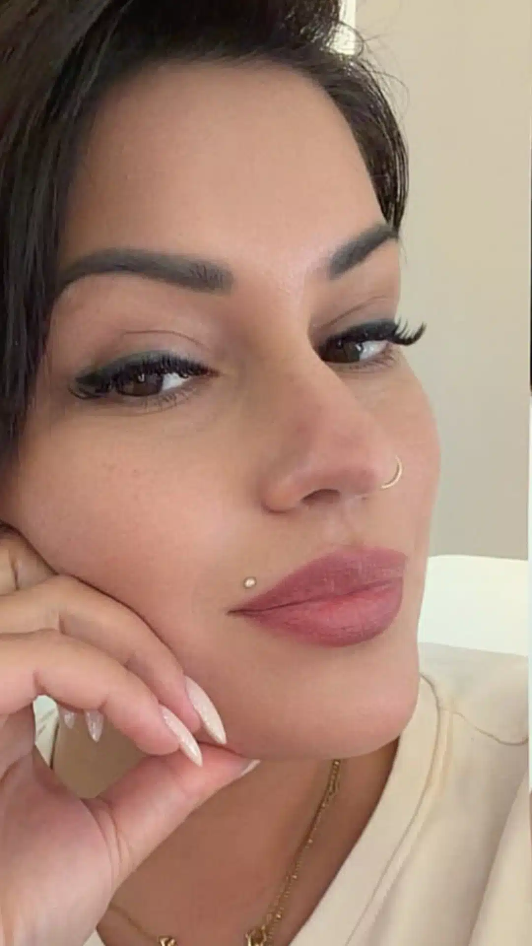 Close-up portrait of a person with a nostril hoop and a Madonna piercing above the upper lip on the left side.