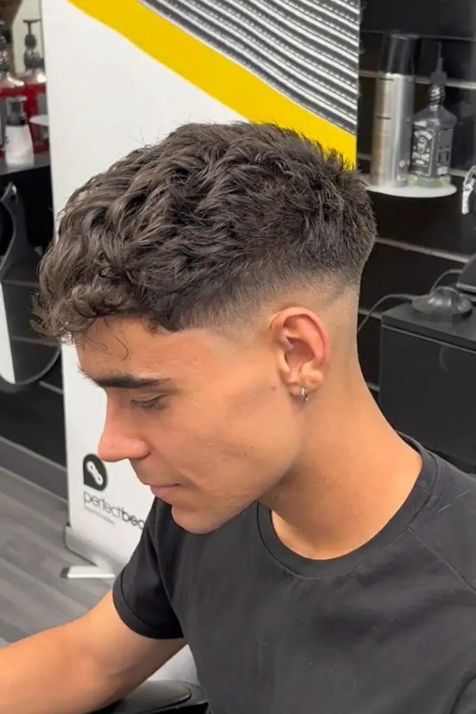 Wavy quiff hairstyle with textured volume on top and faded sides for a modern look