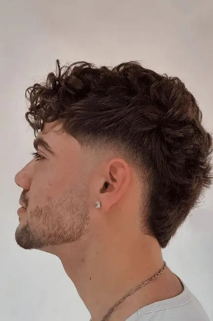 Wavy undercut hairstyle with textured wavy hair on top and closely faded sides